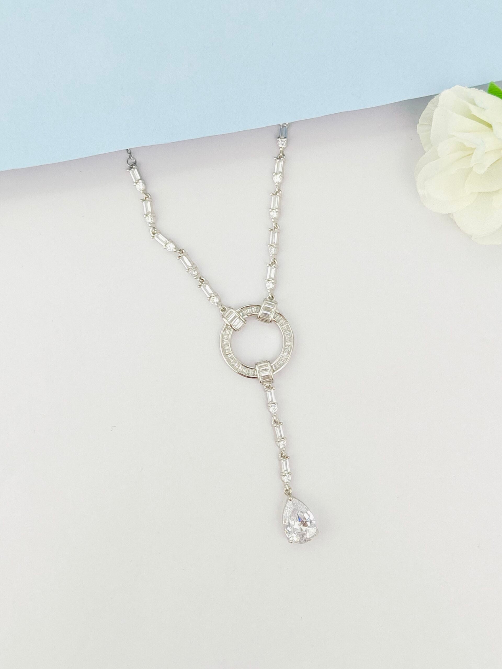 Silver necklace with a key pendant on a mannequin against a light blue background